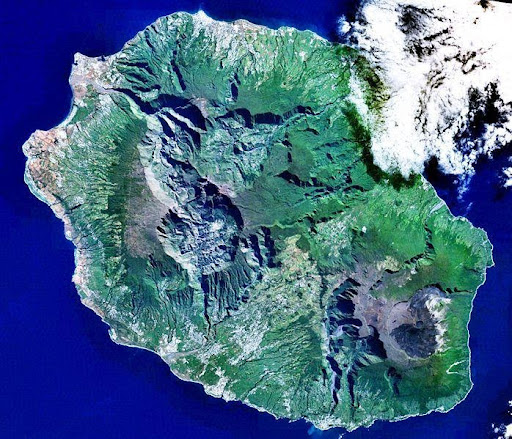 <b>Photographie satellite de l'île de la Réunion montrant un littoral habité et à l'intérieur des terres sauvages.<br></b><i>Reunion 21.12S 55.51E.jpg Par NASA via wikimédia commons, Domaine public, https://commons.wikimedia.org/wiki/File:Reunion_21.12S_55.51E.jpg?uselang=fr</i><br>